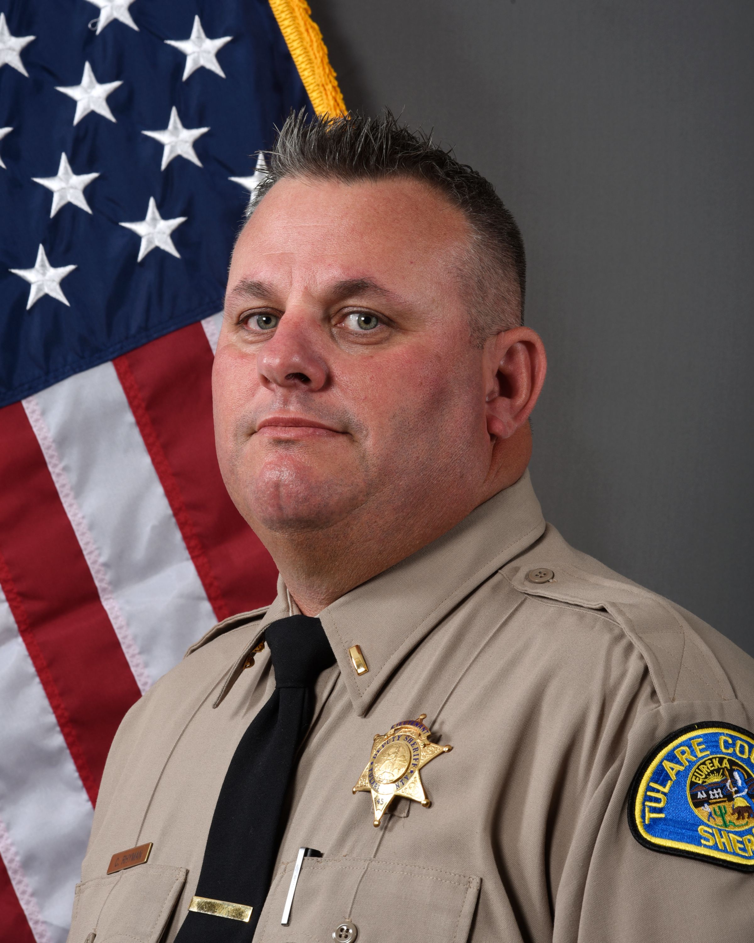 A head and shoulders portrait of Lt. Kevin Kemmerling in uniform in front of the American Flag.